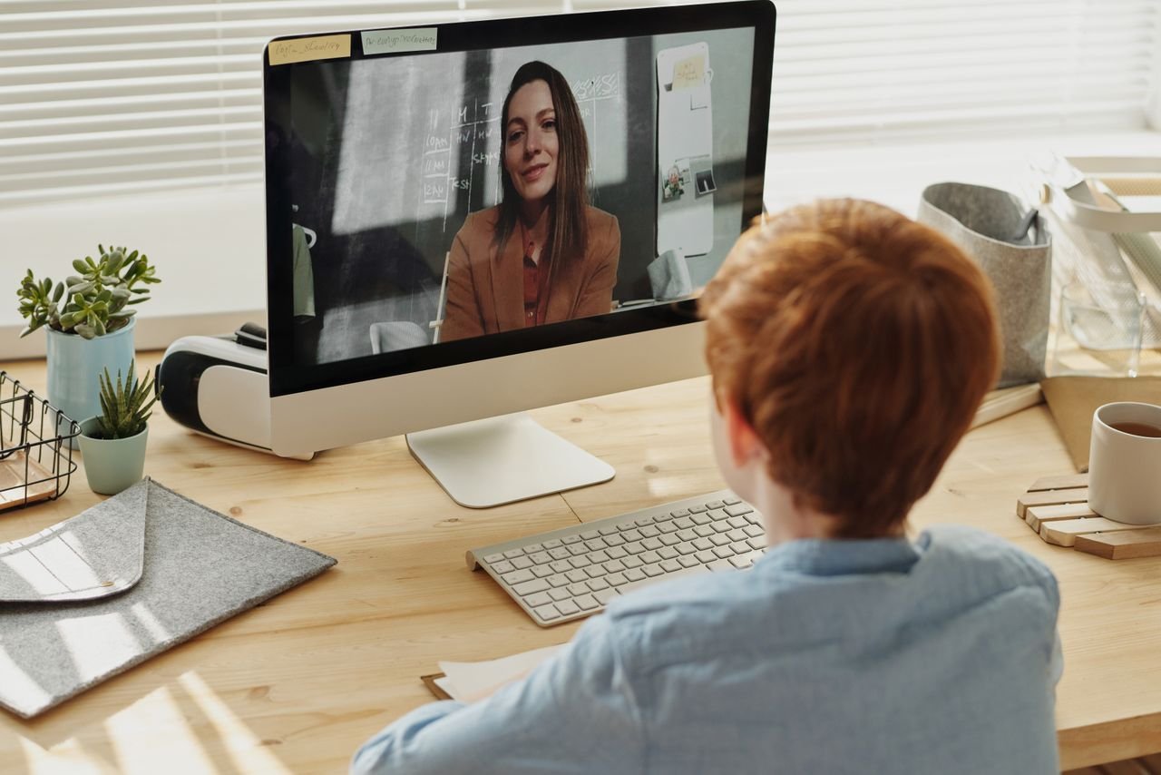 A child participating in an online class at home, focused on the educational content displayed on a desktop computer.